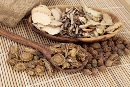 Chinese herbal medicine selection in a wooden spoon, bowl and loose over bamboo mat の写真素材