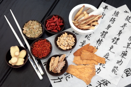 Traditional chinese herbal medicine selection with mandarin calligraphy on rice paper  Translation describes the medicinal functions to increase the bodys ability to maintain body and spirit health and balance energy の写真素材