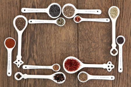 Measuring spoons with herb and spice food ingredients over old oak background の写真素材