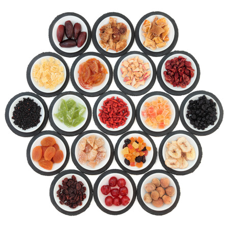 Large dried fruit selection in white bowls on slate rounds over white background の写真素材