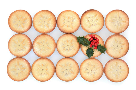 Christmas mince pie cakes and holly over white background の写真素材