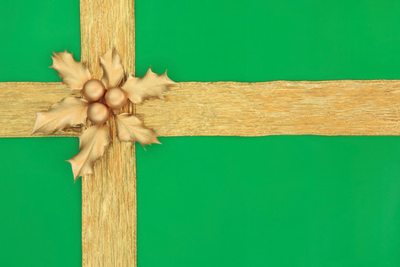 Christmas gift box background in green with gold ribbon, holly and bauble decorations の写真素材