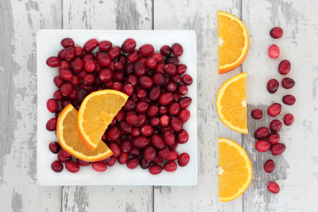 Cranberry and orange fruit over weathered wooden white background.の写真素材