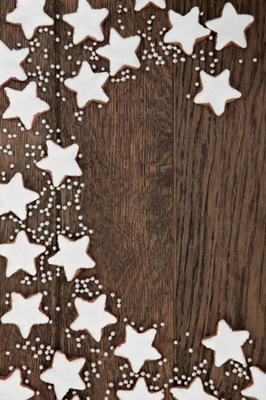 Christmas star gingerbread biscuit background border with silver balls over old oak wood.の写真素材