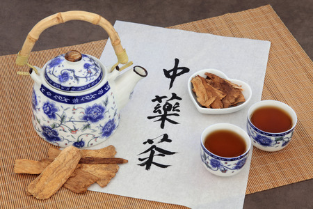 Astragalus herb tea also used in chinese herbal medicine, with cups and calligraphy script on rice paper over bamboo. Translation reads as chinese herbal tea.の写真素材