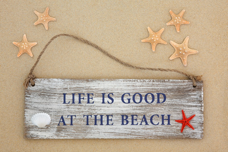 Life is good at the beach sign with starfish and cockle shell on sand background.の写真素材