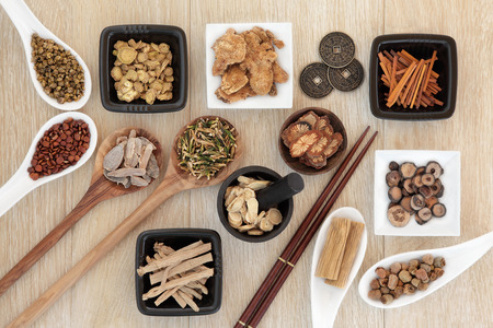 Chinese herbal medicine selection with I ching coins, mortar with pestle and chopsticks over light oak background.の写真素材