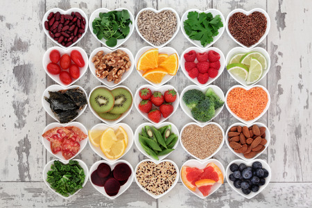 Diet detox super food selection in heart shaped porcelain bowls over distressed wooden background.