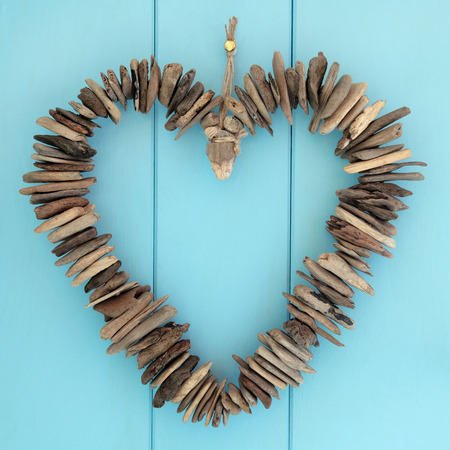 Driftwood heart hanging on a blue oak wood background.の写真素材
