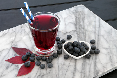 Blueberry juice drink with fresh fruit on marble over dark wood background. High in vitamins, anthocyanins and antioxidants.の写真素材
