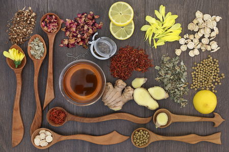 Healthy herbal teas in wooden spoons with glass tea cup and strainer, teas also used in traditional chinese alternative medicine and on oak background.の写真素材