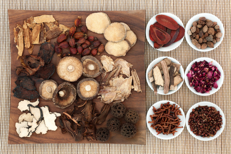 Chinese herb selection used in natural herbal medicine on maple wood board and in porcelain on bamboo background.の写真素材