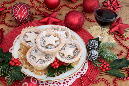 Christmas mince pies with red wine red bauble decorations, holly, ivy, pine cones and fir on oak wood background.の写真素材