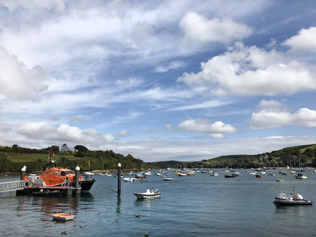 Salcombe Harbour, West Hams, Devon, United Kingdom. 29th August 2017. Salcombe harbour with the RNLI lifeboat moored to posts with small sailing craft, ribs and speed boats on the water on a cloudy blue sky summers day.のeditorial素材