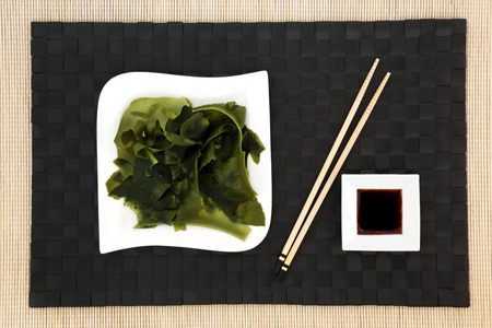 Japanese wakame seaweed food with low sodium soy sauce on porcelain dishes on bamboo background with chopsticks. Has many health benefits and is very high in minerals.の写真素材