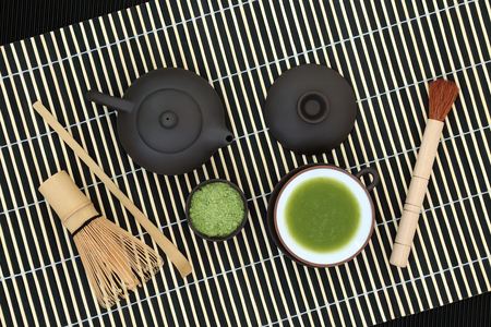 Japanese green matcha tea with powder and drink in a cup with whisk, brush and scoop on bamboo background. Health drink concept.の写真素材