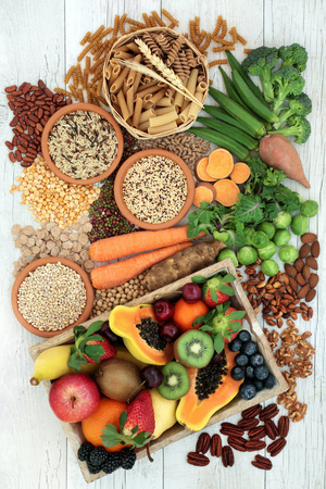 Health food for a high fiber diet with whole wheat pasta, grains, legumes, nuts, fruit, vegetables and cereals with foods high in omega 3 fatty acids, antioxidants and vitamins. Rustic background top view.の写真素材