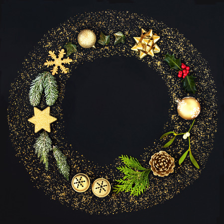 Christmas wreath garland with gold glitter, bauble decorations and winter flora on black background.Top view. Festive Christmas card for the holiday season.の写真素材