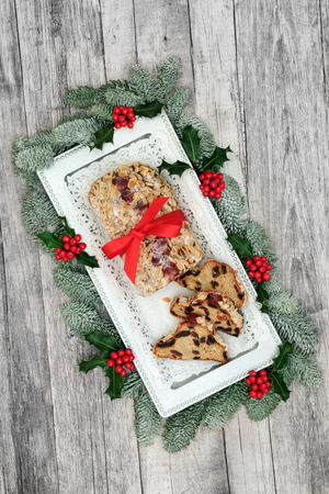 Stollen Christmas cake with winter flora on a silver plate on rustic wood table background....