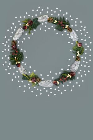 Christmas and winter wreath with snow covered spruce fir, mistletoe, acorns, cedar leaves, ivy and loose snowflakes on grey background with copy space.の写真素材