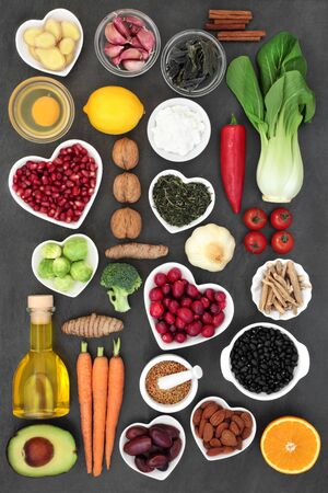 Super food to slow the ageing process concept including fruit, vegetables, nuts, herbs, spices, green tea, olive oil and dairy. Very high in antioxidants, anthocyanins, dietary fibre and vitamins. Top view on slate.の写真素材