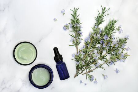 Vegan skin care beauty treatment with rosemary herb flowers, aromatherapy essential oil and moisturiser on marble.の写真素材