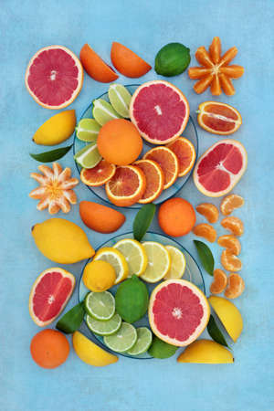 Large collection of citrus fruit with oranges, lemons, limes & grapefruit high in antioxidants, anthocyanins, lycopene, fibre & vitamin c. Immune boosting health care concept. On mottled blue.の写真素材
