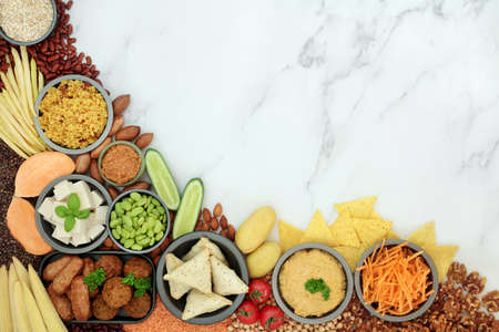 Healthy lifestyle food for vegan diet with vegetables, legumes, tofu meat substitute products, cereals, nuts & snacks. High in protein, omega 3, antioxidants, fibre, vitamins & minerals. Flat lay on marble.の写真素材