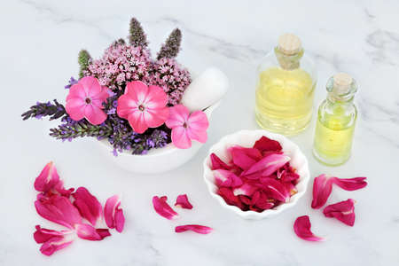Essential oil preparation for aromatherapy and natural herbal plant medicine. Summer, nature, flowers, herbs, oil bottles. Alternative nature health care concept. On marble background.の写真素材