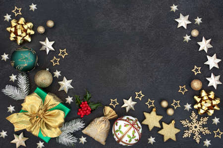 Christmas border with gift box, bauble decorations, stars, snow covered fir and holly on grey...