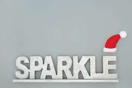 Sparkle at Christmas concept with silver glitter sign and santa hat on grey background. Minimal abstract composition for the Xmas and New Year festive season. Top view.の写真素材