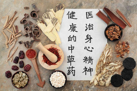 Ancient Chinese herbal medicine with herbs, spice and calligraphy script on rice paper. Translation reads as traditional Chinese herbs to heal mind body and spirit. Natural health care concept.の写真素材