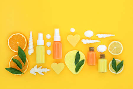 Refreshing lemon and orange citrus fruit beauty treatment for skincare. Moisturiser, lotion, soap, sponge and seashells on yellow background. Natural health care skin tonic concept.の写真素材
