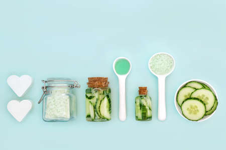 Cucumber natural cosmetic beauty treatment with fresh slices, soap, gel and ex foliation salts. Alternative health care concept. On blue background with copy space.の写真素材