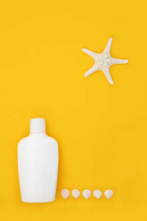 Sunscreen suntan lotion bottle for UV summer sunbathing protection on yellow background with starfish, cockleshell seashells. Skincare health concept. Minimal composition, copy spaの写真素材