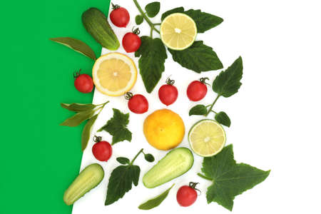 Freshly grown local produce of salad tomatoes, cucumber, lemon and lime citrus fruit with leaves on dual tone  green white background. High in antioxidants, fibre, anthocyanins, lycopene, vtamin c.の写真素材