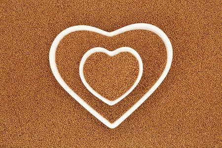 Camelina seed for low cholesterol. Health food to reduce LDL levels for cardiovascular heart benefits with oil high in vitamin E for skincare. In heart shaped dishes. Top view flat lay.の写真素材