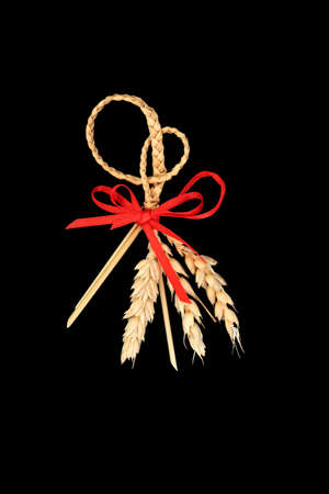 Natural plaited straw corn husk doll. Traditional pagan wiccan fertility symbol used in old fashioned European farming harvest rituals. On black. Top view.の写真素材