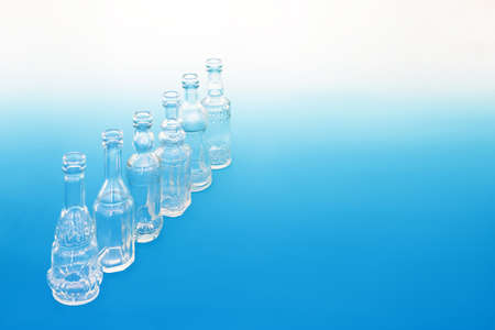 Old fashioned glass bottles in a diagonal line on gradient blue white background. Retro abstract theme creative design concept.の写真素材