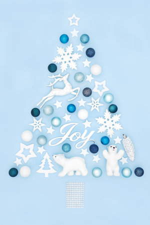 Christmas tree concept shape with Joy sign and tree bauble decorations on pastel blue background. North Pole fantasy surreal abstract for winter Xmas and New Year.の写真素材
