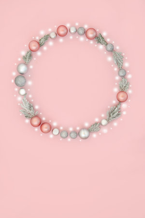 Fantasy Christmas wreath with abstract snow and tree bauble ornaments on pastel pink background. Magical festive composition for winter Xmas and New Year.の写真素材