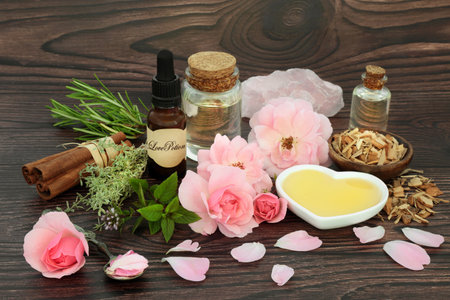 Mystical love potion and herbal and floral ingredients for magic spell. Herbs, rose flowers, honey oil and rose quartz crystal. Wiccan and shamanic mystical tradition for lovers and Valentines Day.の写真素材