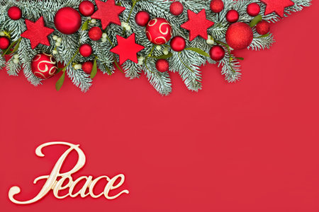 Christmas peace on earth concept with winter fir and snow, tree decorations on red background. Festive border composition for traditional Xmas and New year holiday season.の写真素材
