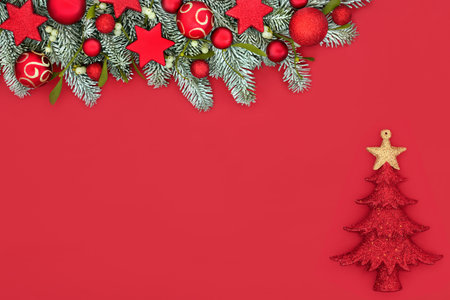 Magical Christmas winter fir and snow red background border composition with baubles and tree decoration. Festive fun design for traditional Xmas holiday season.の写真素材