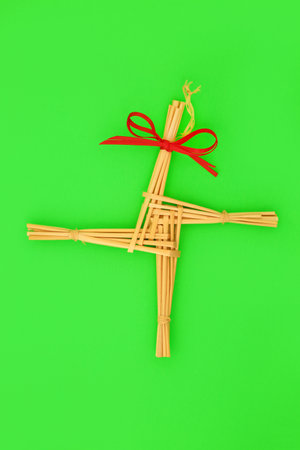 Saint Brigids Cross Irish pagan symbol of house protection blessing against fire and evil. Traditionally made in Ireland on Imbolc first day of Spring on St Brigids feast day. On green, top view.の写真素材