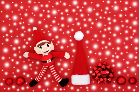 Christmas eve snow red background with santa symbols of elf, hat, tree bauble decorations and bow....