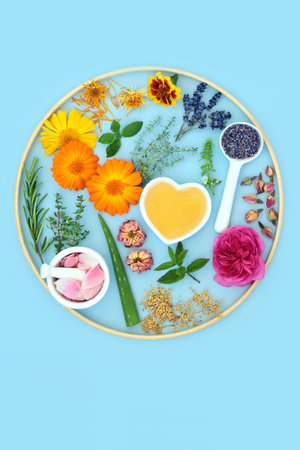 Natural ingredients for floral skincare beauty treatments with honey, flowers and herbs  Can ease psoriasis, eczema, acne and wounds. Alternative floral healthcare circular design on blue background.の写真素材
