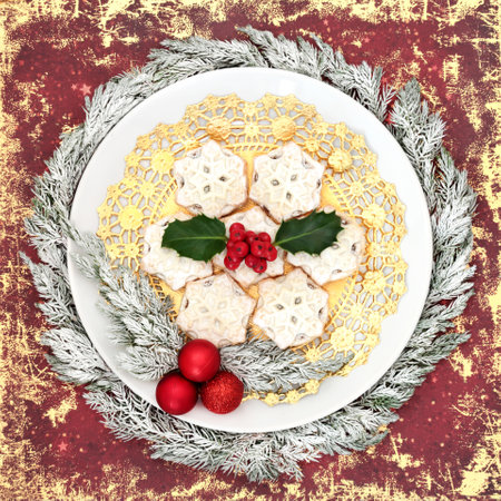 Festive Christmas traditional mince pies on white plate with winter holly, snow covered juniper fir, tree decorations on grunge red background. Food design for Xmas and New Year.の写真素材