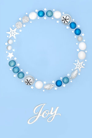 Christmas joy sign with wreath and tree bauble decorations on pastel blue background. Festive fantasy abstract concept for winter Xmas and New Year.の写真素材