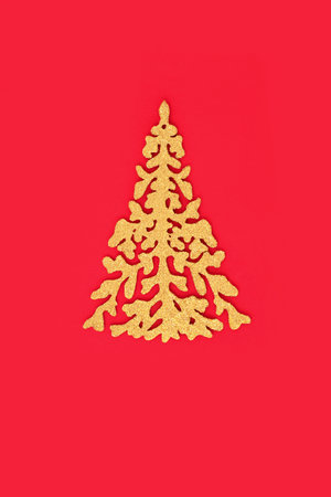 Festive gold glitter ornate Christmas tree on red background, Minimal traditional design for Xmas and New Year holiday season.の写真素材